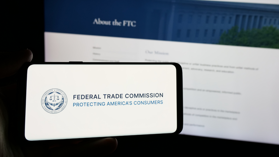 Smartphone displaying the Federal Trade Commission logo with blurred FTC website in background, representing consumer protection.